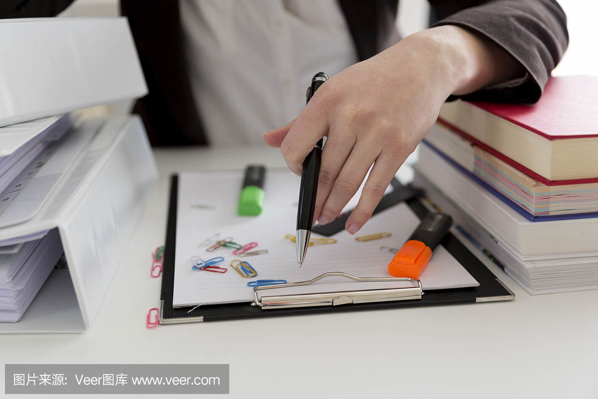 坐在滿是文書,書籍和文件的桌子旁的女人。混亂的工作場(chǎng)所。過載和過度勞累